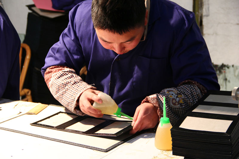 Team assembling custom menu covers in Menunique production operation